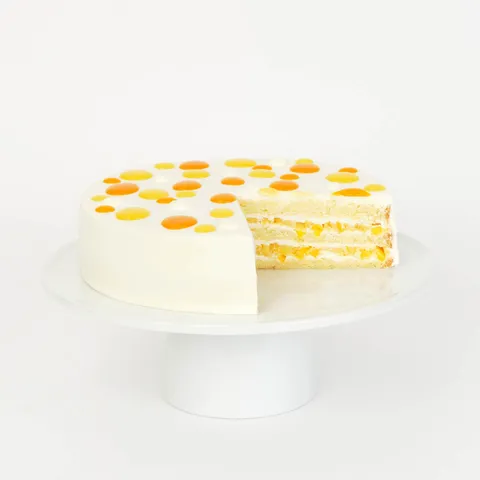A thumbnail shot of a sliced into Lady M Mango Shortcake on top a white cake stand.