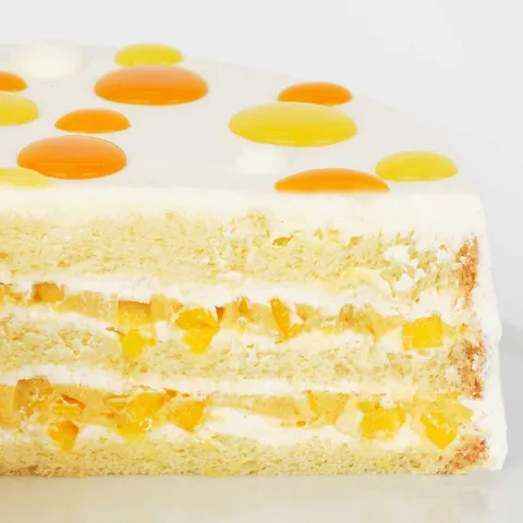 A detail shot of a Lady M Mango Shortcake. Layers of vanilla sponge cake, purée, and diced mangoes.