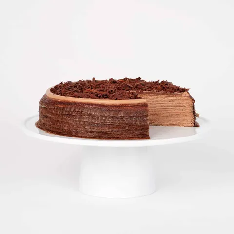 A thumbnail shot of a sliced into Lady M Amedei Chocolate Mille Crêpes on top a white cake stand.