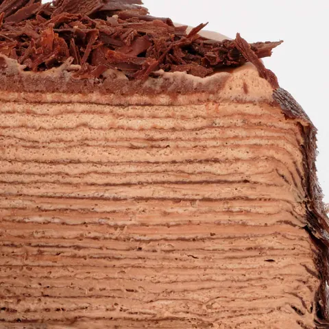 A detail shot of a Lady M Amedei Chocolate Mille Crêpes. Layers of cream, crêpes, and chocolate.