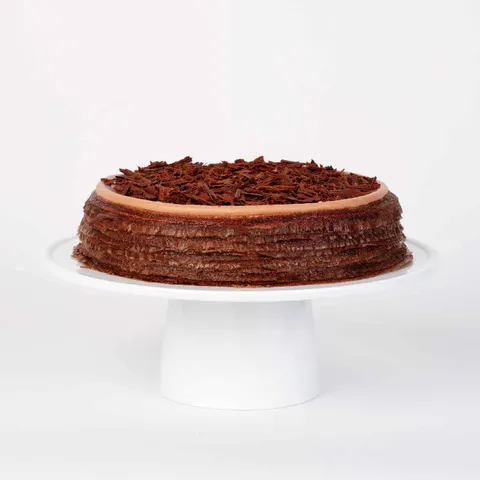 A thumbnail shot of a Lady M Amedei Chocolate Mille Crêpes on top a white cake stand.