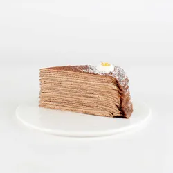 A thumbnail shot of a Lady M Chocolate Banana Mille Crêpes slice on top a white round plate.