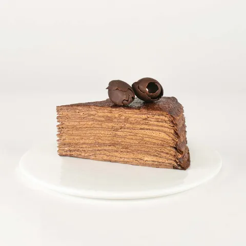 A thumbnail shot of a Lady M Chocolate Mille Crêpes slice on top a white round plate.