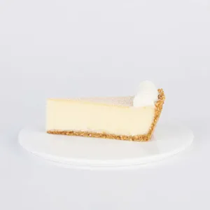 A slice of Lady M's Coconut Cheesecake on a white plate.