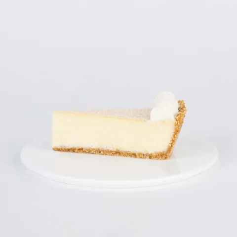 A slice of Lady M's Coconut Cheesecake on a white plate.