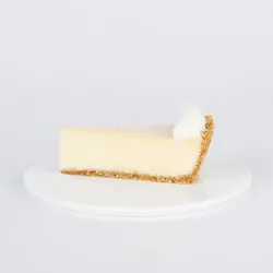 A slice of Lady M's Coconut Cheesecake on a white plate.