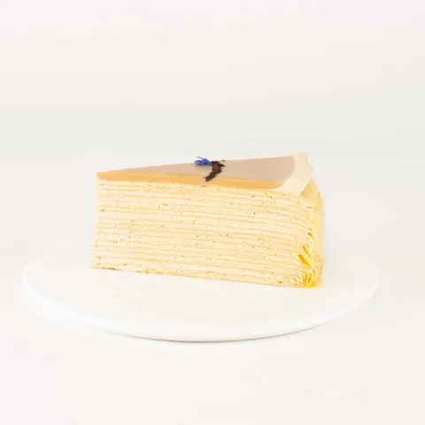 A thumbnail shot of a Lady M Earl Grey Mille Crêpes slice on top a white round plate.
