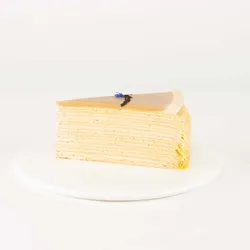 A thumbnail shot of a Lady M Earl Grey Mille Crêpes slice on top a white round plate.