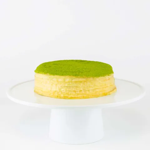 A thumbnail shot of a 6-inch Lady M Green Tea Mille Crêpes on top a white cake stand.