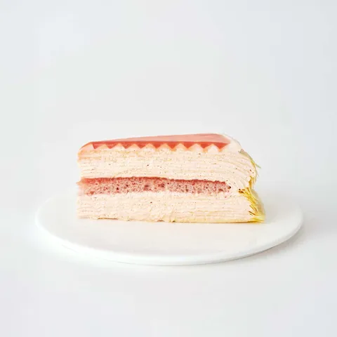 A thumbnail shot of a Lady M Guava Mille Crêpes slice on top a white round plate.