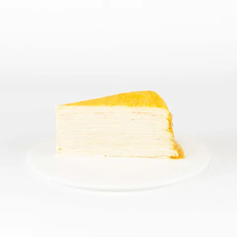 A thumbnail shot of a Lady M Signature Mille Crêpes slice on top a white round plate.