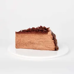 A thumbnail shot of a Lady M Amedei Chocolate Mille Crêpes slice on top of a white round plate.