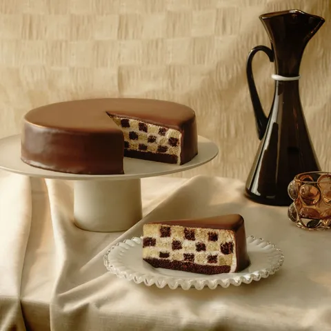 A Lady M Checkers with one slice served on a plate over a beige linen.