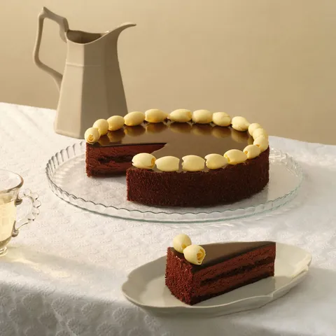 A Lady M Couronne Du Chocolate with one slice served on a plate over a white linen.