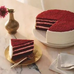 A Lady M Red Velvet with one slice served on a plate over a marble table top.
