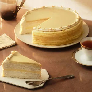 A Lady M Jasmine Calamansi Mille Crêpes with one slice served on a plate, set on a glass table.