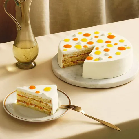 A Lady M Mango Shortcake with one slice served on a plate, set over a white linen.