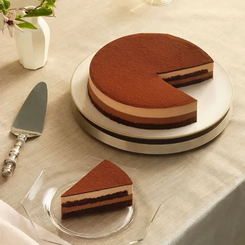 A Lady M Chocolate Arc-en-Ciel with one slice served on a plate over a beige linen.