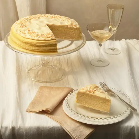 A Lady M Tres Leches Mille Crêpes with one slice served on a plate set on a white linen.