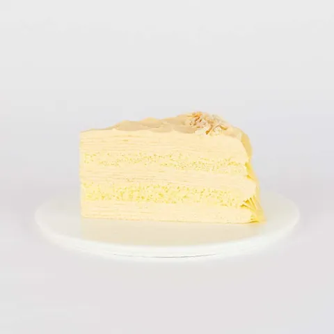 A slice of Lady M's Tres Leches Mille Crêpes, on top a white round plate.