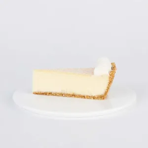 A slice of Lady M's Coconut Cheesecake, on top a white round plate.