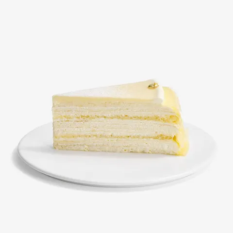 A slice of Lady M's Dassai Blue Mille Crêpes, on top a white round plate.