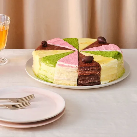 A Lady M Slice of the Best: Summertime Collection on a cake plate over a beige linen.