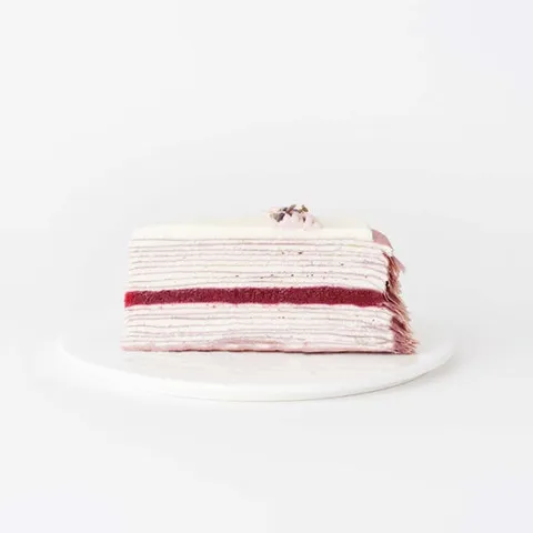A slice of Lady M's Lavender Mille Crêpes on top a white round plate.