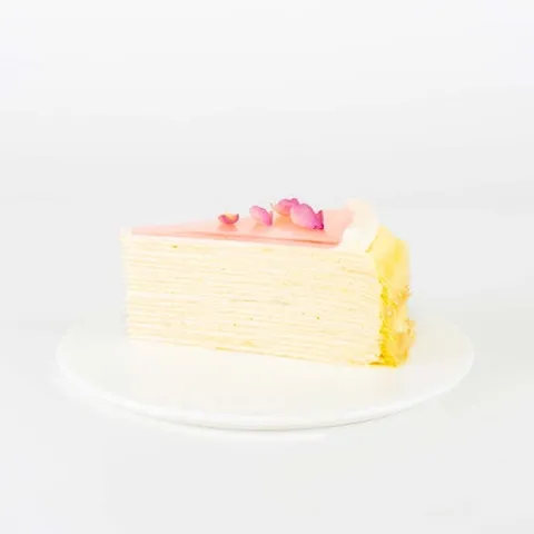 A slice of Lady M's Rose Mille Crêpes on top a white round plate.