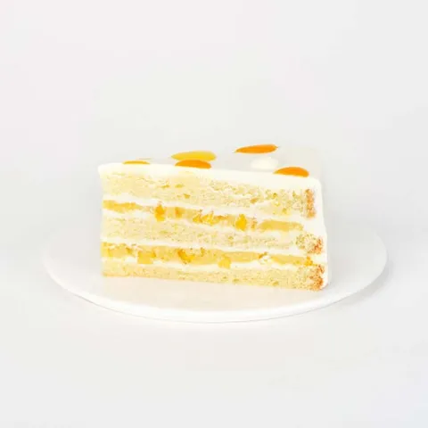 A slice of Lady M's Mango Shortcake on top a white round plate.