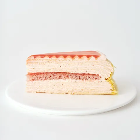 A slice of Lady M's Guava Mille Crêpes on top a white round plate.