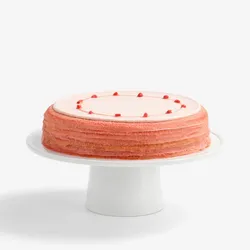 A thumbnail shot of a whole Lady M's Strawberry Matcha Mille Crêpes on top a white cake stand.