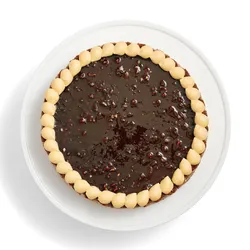 A top-down shot of a whole Lady M's Noisettes Chocolat cake on top a white round cake stand.