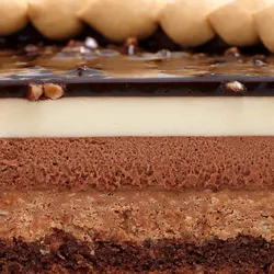 Detail shot of Lady M's Noisettes Chocolat cake. Chocolate biscuit base, mousse, glaze, & hazelnuts.