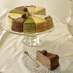 A Lady M Black Slice of the Best: Celebration Collection with one slice served on a beige linen.