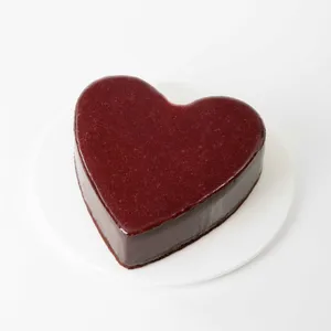 A whole Framboise au Chocolat Valentine Heart cake on top of a white round cake plate.