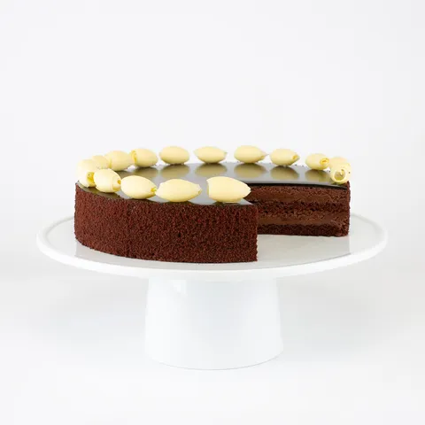 A Lady M Couronne du Chocolat sliced into, sitting on top of a white round cake stand.