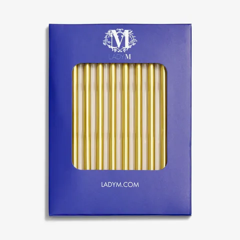 Gold Lady M candles in blue box on white background.