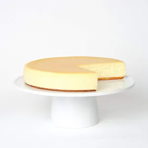 Light and creamy Gateau Fromage cheesecake on a cake stand, with one slice missing.