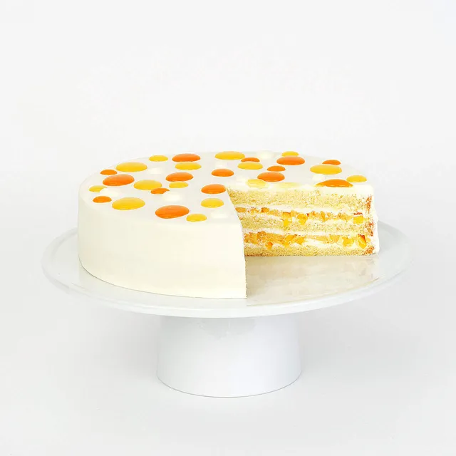 Mango shortcake with cream frosting, dotted top, and a slice revealing mango-filled layers.