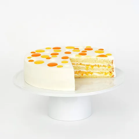 Mango shortcake with cream frosting, dotted top, and a slice revealing mango-filled layers.