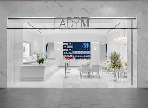 Lady M Tysons Galleria elegant storefront: marble exterior, "LADY M" logo, white interior, cake counter, blue display wall, white tables.