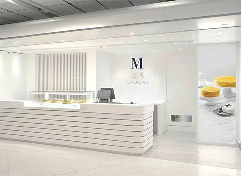 Lady M HK Airport: white striped counter, small cake display, logo on white wall, POS, digital cake display. Elegant.