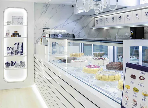 Lady M Causeway Bay HK: elegant cake display, Signature Crêpes, white stripes, marble walls, crystal chandelier, lit shelves.