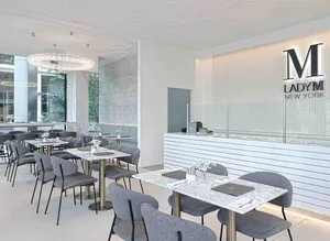 Lady M South Beach Singapore: gray chairs, marble tables, striped counter, blue logo, crystal chandelier. Elegant.