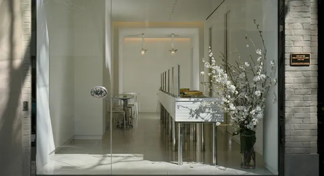 Elegant glass storefront of Lady M Upper East Side Boutique featuring a clean white interior and cake display visible through a large window