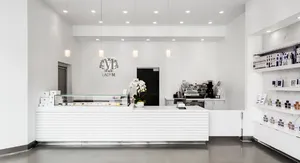 Lady M San Diego interior with white design, cake display, logo, pendant lights, and orchid.