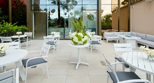 Lady M Las Vegas outdoor seating with white tables, gray cushions, flowers, and lounge chairs.