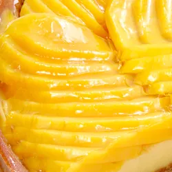 Closeup of Lady M’s Tarte à la Mangue with glossy mango slices, passion fruit cream, and crust.