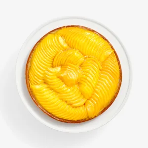 Overhead of Lady M’s Tarte à la Mangue with mango slices and a glossy glaze on a golden crust.